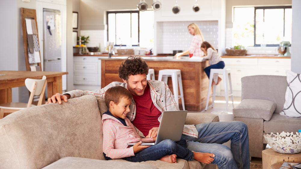 Vater und Sohn auf Sofa mit Lernlaptop