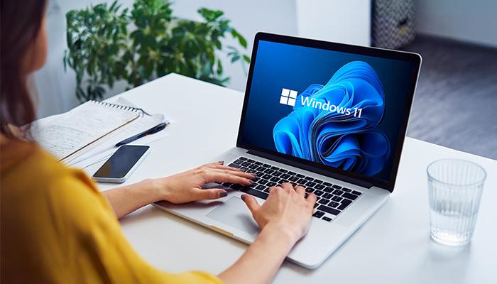 Ein aufgeklappter silberner Laptop mit Windows 11 Logo auf dem Bildschirm.