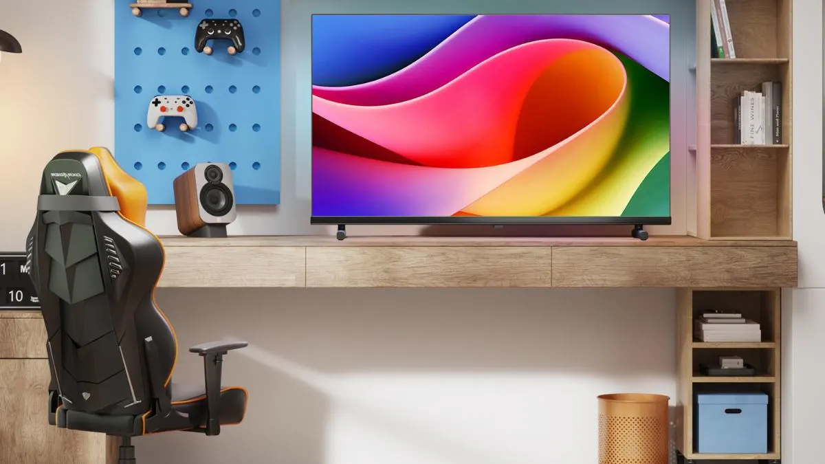 Der 32-Zoll-Fernseher Hisense 32A5Q steht auf einem Schreibtisch neben einem Lautsprecher und einem Gaming-Stuhl. An einem Wandregal hängen zwei Gaming-Controller.