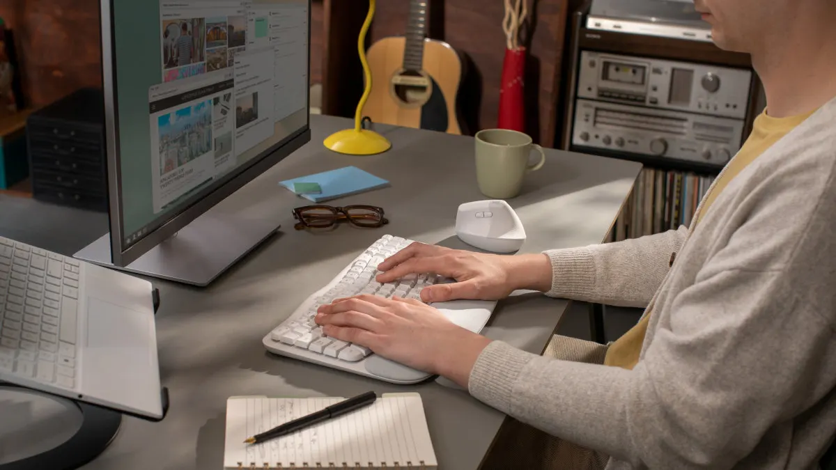 Eine Person sitzt an einem Schreibtisch, ihre Hände liegen auf der ergonomischen Tastatur Logitech Wave Keys.