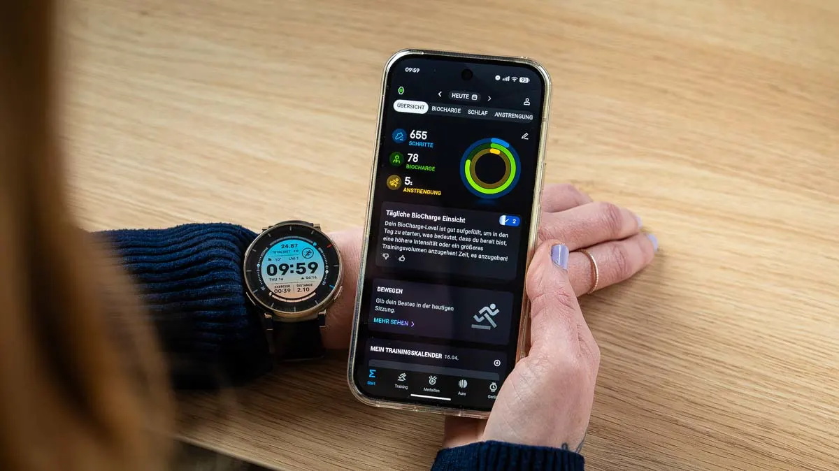 Franzi hält ihr Smartphone mit der Startseite der Zepp-App neben die Amazfit Active 3 Premium an ihrem Handgelenk.