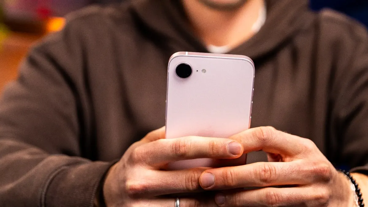 Niklas hält das iPhone 17e mit beiden Händen und bedient es.