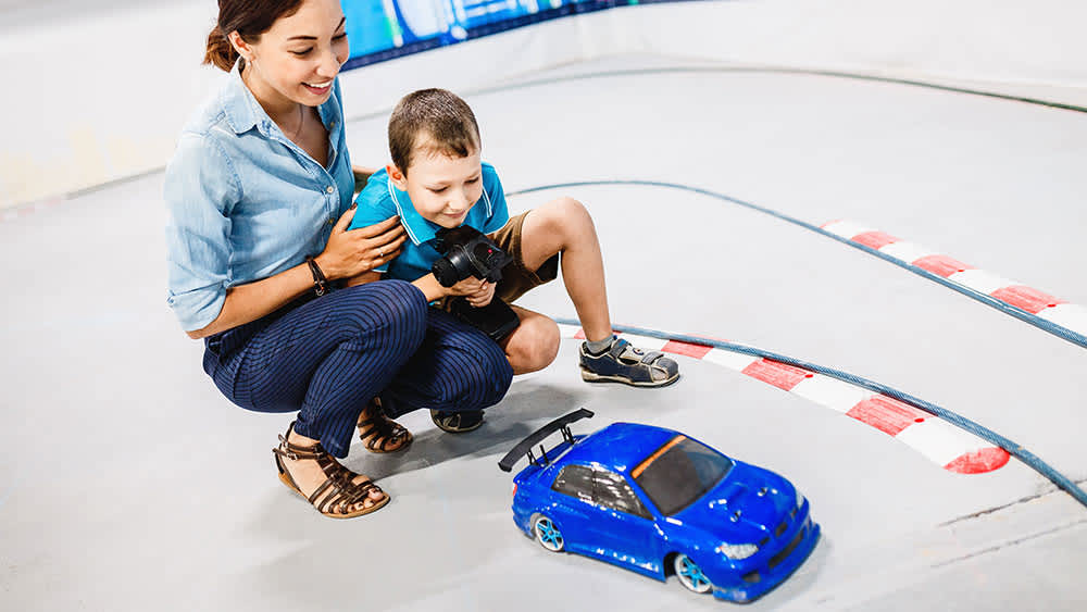 Mutter und Junge spielen mit ferngesteuertem Auto
