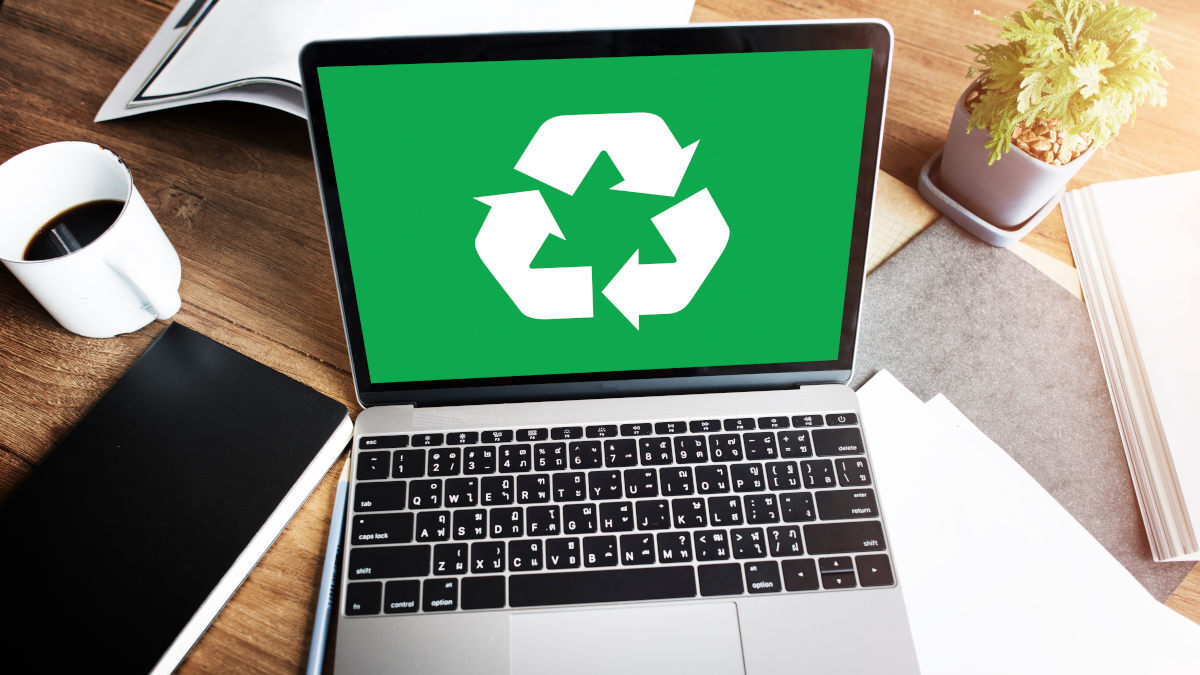 Ein Laptop mit einem Recycling-Logo auf dem Display steht auf einem Schreibtisch.