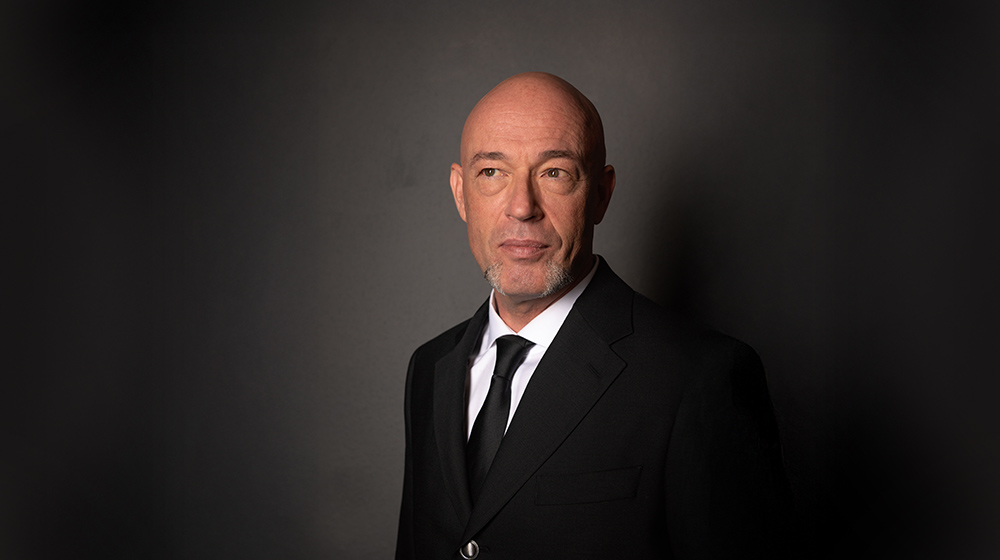 Portraitfoto von „Der Graf“, Sänger und Produzent der Band Unheilig vor dunklem Hintergrund.