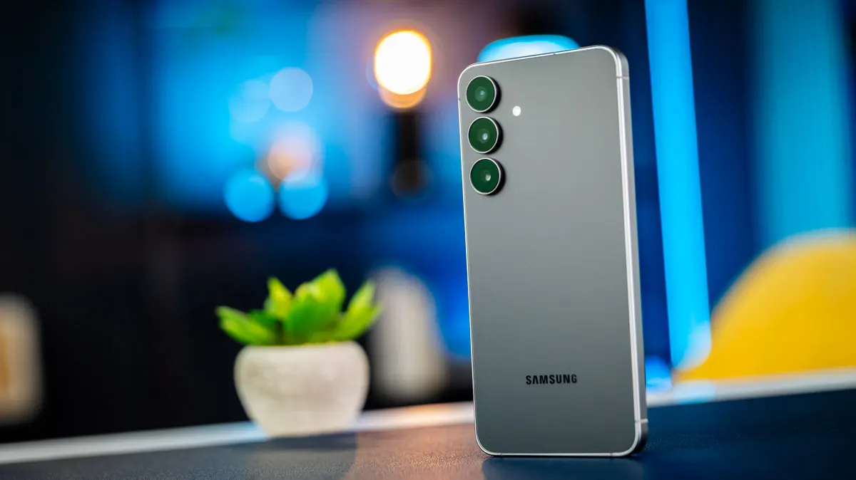 Das Smartphone Samsung Galaxy S25 FE steht auf einem Tisch. Im Hintergrund erkennt man eine Pflanze.