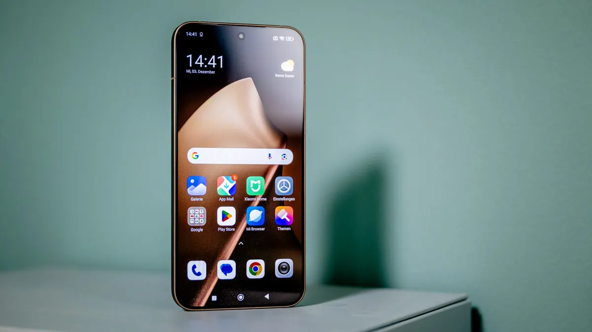 Das Smartphone Xiaomi 15T Pro steht mit eingeschaltetem Display vor einer grünen Wand.