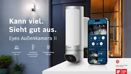 Eine Bosch Eyes Außenkamera II neben einem Smartphone, das die Kameraansicht zeigt. Text: "Kann viel. Sieht gut aus."