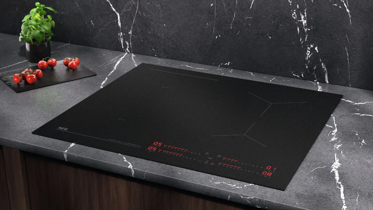 Das Induktionskochfeld AEG TI64IB1FIZ eingelassen in einer grauen Arbeitsplatte einer Küche.