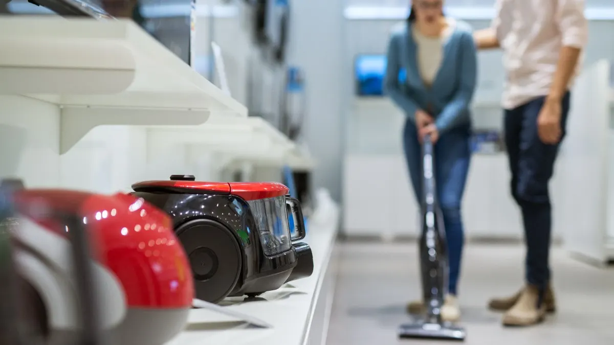 Eine Frau und ein Mann probieren einen Staubsauger im Fachhandel aus.