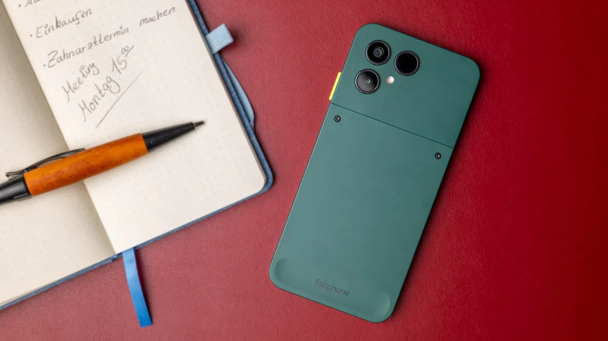 Das Fairphone 6 liegt mit der Rückseite nach oben neben einem Notizbuch.