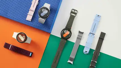 Auf farbigem Grund liegen drei Smartwatches mit Wechselarmbändern in Rosa, Weiß, Grün, Blau und Silber.