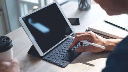 Ein Mann sitzt vor einem Tisch vor einem Tablet mit Tastatur und Stift.