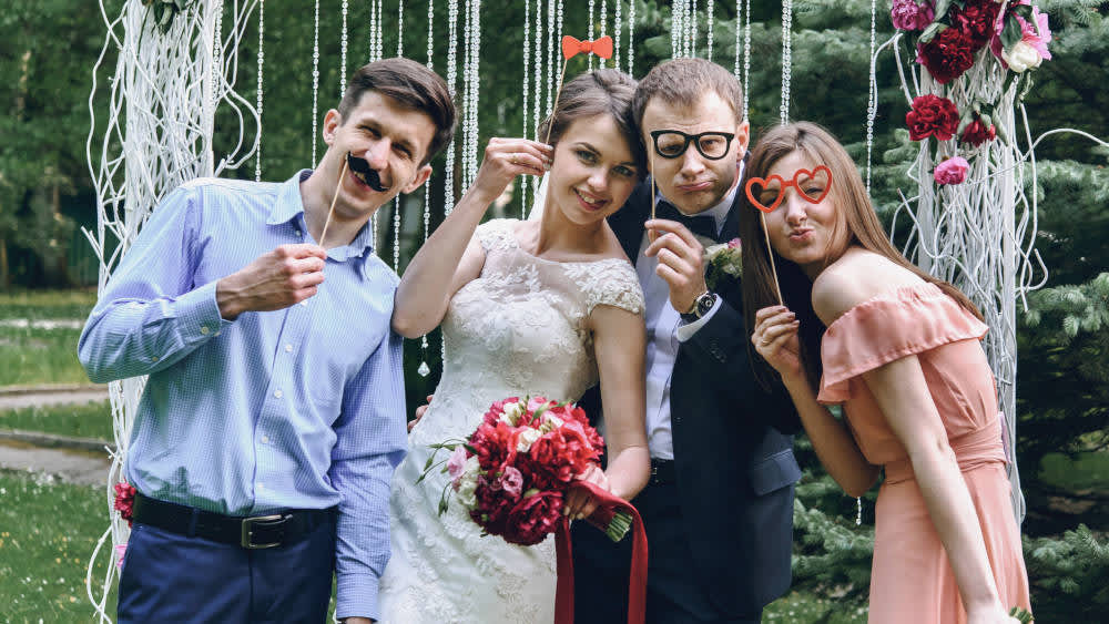 Ein Hochzeitspaar macht lustige Fotos mit den Gästen.