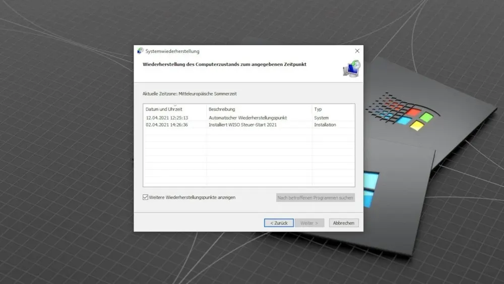 Systemwiederherstellung-Dialogfenster mit Datumsangaben, Beschreibungen und Typen neben einem grauen Ordner mit einem bunten Logo.