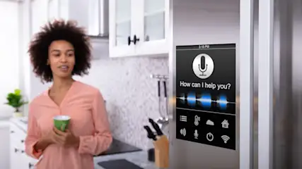 Eine Frau hält eine Tasse in der Küche, während ein Kühlschrank mit Touchscreen-Display zu sehen ist.