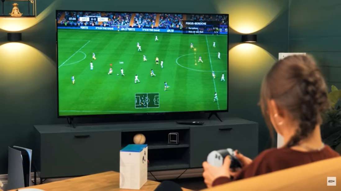 Eine Frau hält einen PlayStation-Controller in den Händen und spielt FIFA.