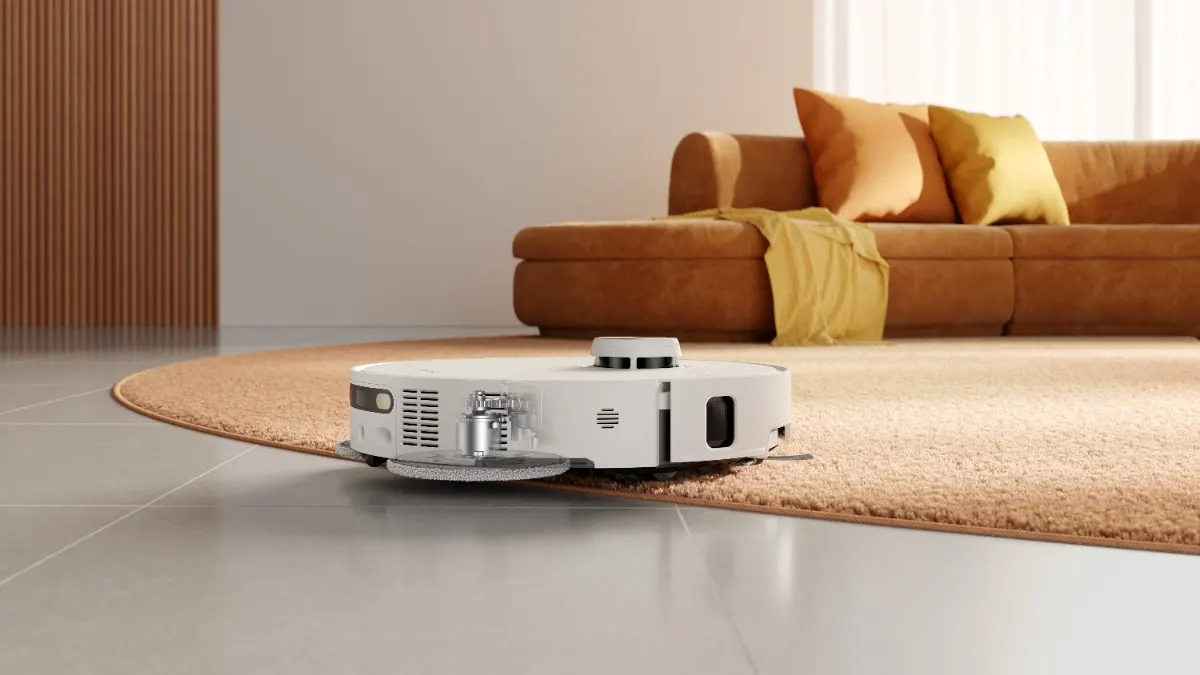 Der Dreame L50s Pro Ultra fährt auf einen Teppich, dahinter steht ein Sofa.