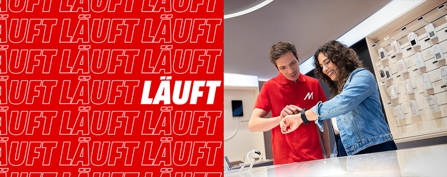 Roter Hintergrund mit weißem "LÄUFT"-Text links. Rechts prüft ein Mann in rotem Hemd eine schwarze Smartwatch am Handgelenk einer Frau in Jeansjacke.