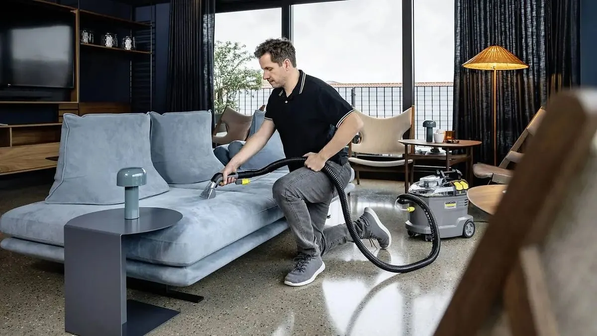 Ein Mann reinigt ein Sofa mit dem Kärcher Puzzi 8/1.