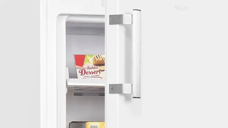 Ein weißer Kühlschrank mit einem silbernen Griff, dessen Tür leicht geöffnet ist, enthüllt ein Dessert im Inneren.