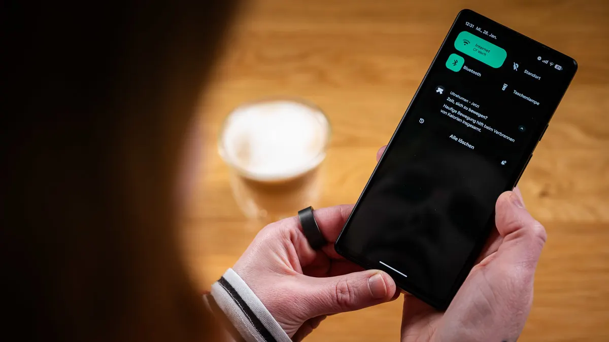 Franzi trägt den Ultrahuman Ring Air am linken Zeigefinger und schaut eine Push-Benachrichtigung der Ultrahuman-App an.