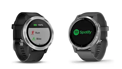 Zwei Smartwatches mit schwarzen Armbändern. Auf einem Display stehen "Run", "Bike" und "Pool". Das andere Display zeigt das Spotify-Logo.