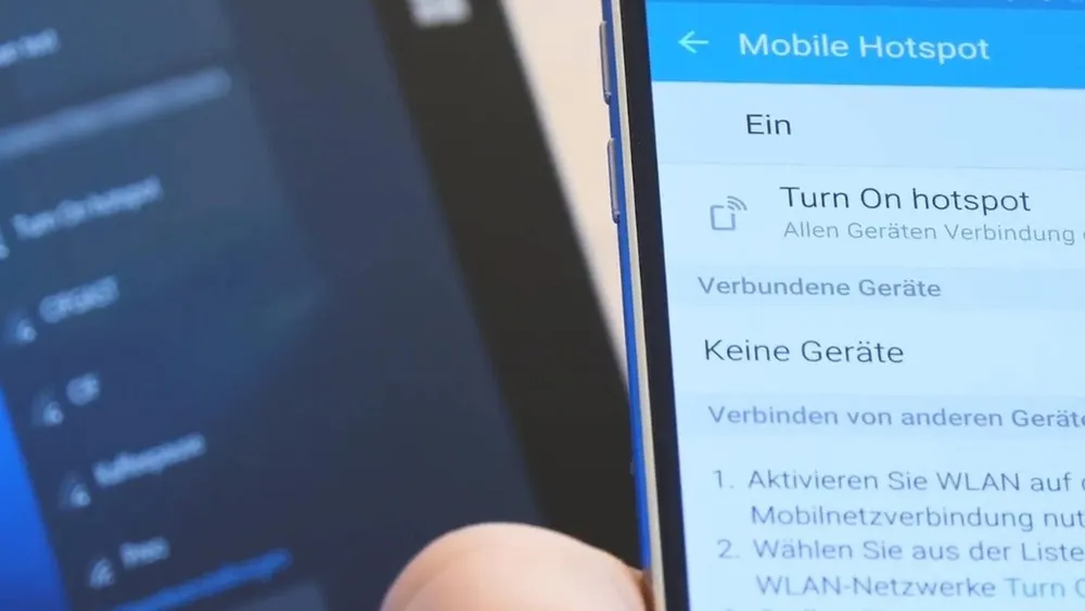 Nahaufnahme von zwei Geräten, auf denen Text angezeigt wird, darunter "Mobile Hotspot" und Anweisungen zum Verbinden.