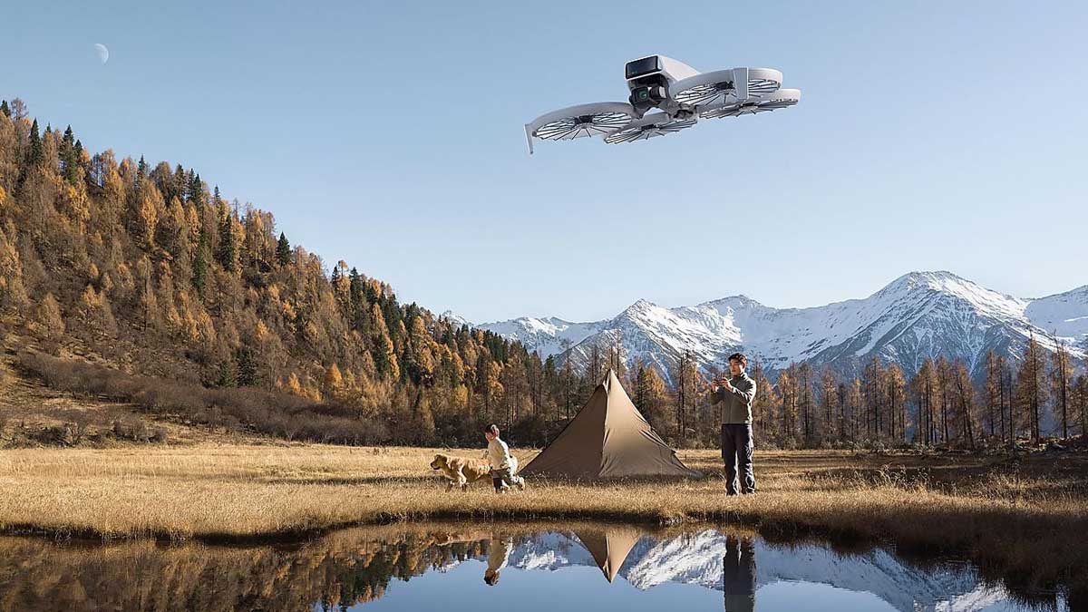 Eine Person fliegt die Mini-Drohne DJI Flip über einen See, an dessen Ufer ein Zelt aufgebaut ist.