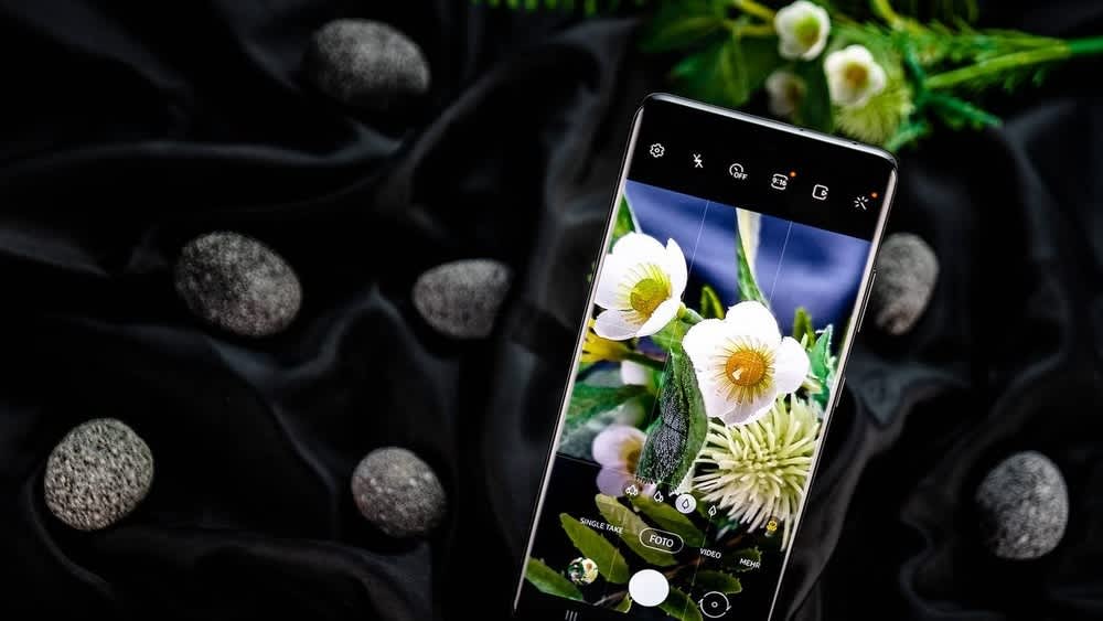 Ein Samsung Galaxy S21 Ultra mit offener Kamerafunktion liegt vor einem schwarzen Tuch mit Steinen drauf.