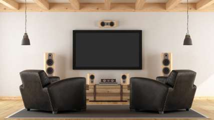 Ein Fernseher hängt an einer Wand im Wohnzimmer und ist an ein Soundsystem angeschlossen.