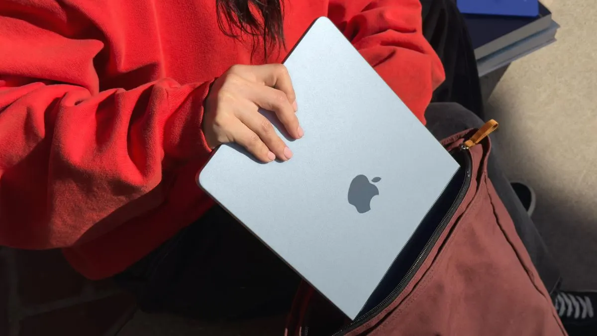 Eine Person steckt das Apple MacBook 13 M4 in einen Rucksack.