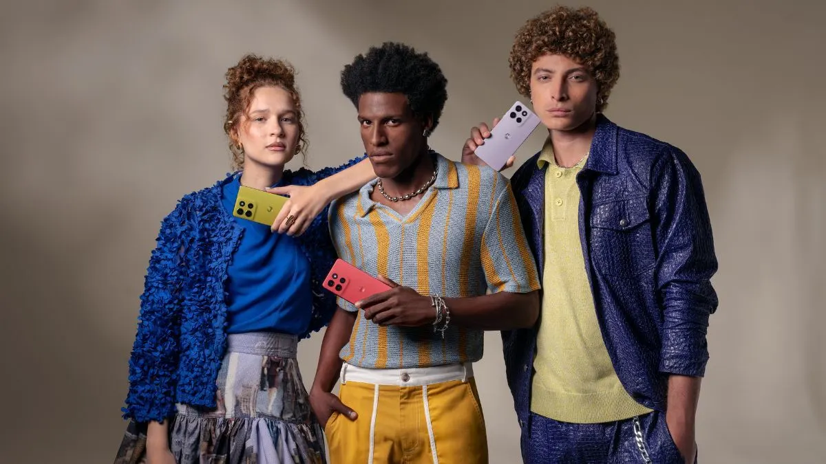 Drei Personen stehen vor einer grauen Wand und halten jeweils ein Motorola moto g86 5G Smartphone in der Hand.