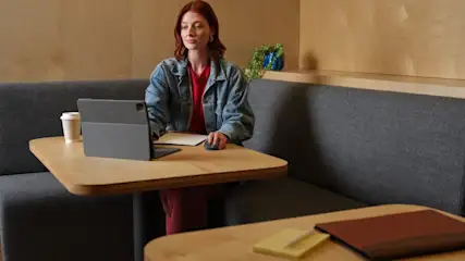 Eine Frau sitzt an einem Tisch vor der Tastatur einer iPad-Hülle von Logitech.