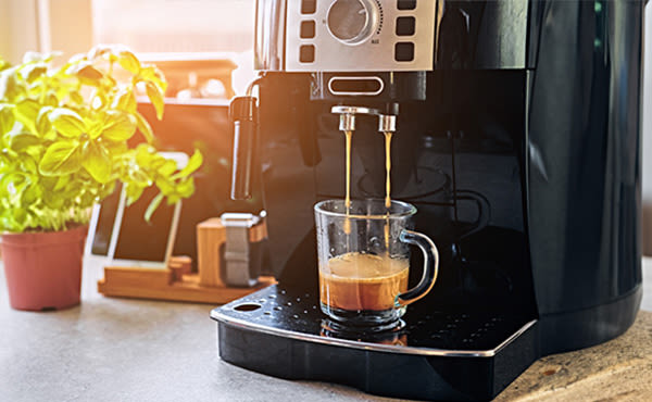 Kaffee läuft aus einem Kaffeevollautomaten in eine Tasse.