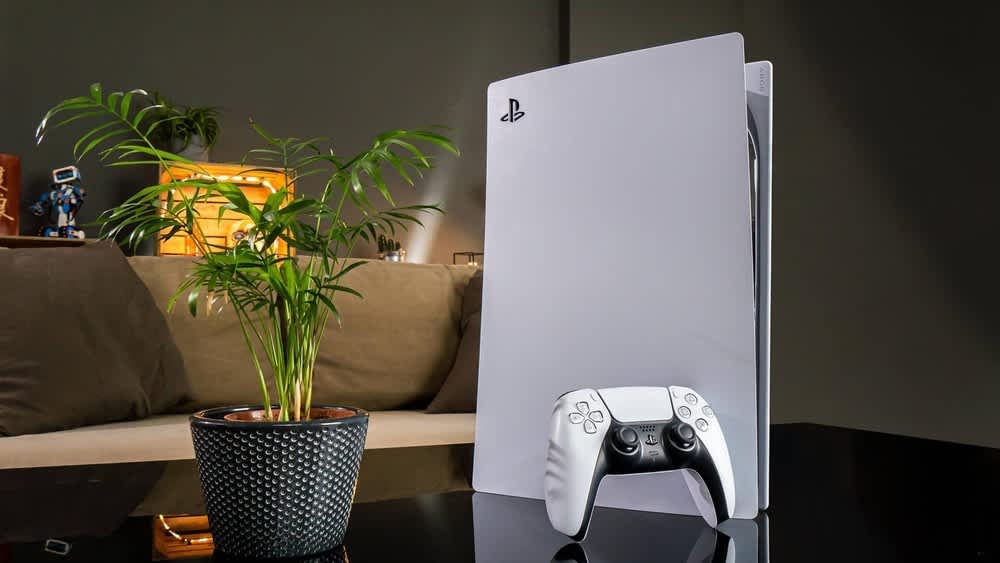 Eine PlayStation 5 mit einem Controller steht auf einem Wohnzimmertisch.