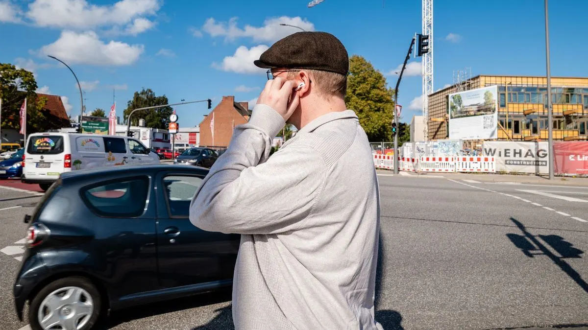 Andreas steht vor einer befahrenen Straße und bedient die AirPods Pro 3 mit einer Hand.