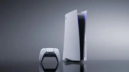 Weiße Spielkonsole PlayStation 5 und passender Controller auf dunkler, reflektierender Oberfläche vor grauem Hintergrund.