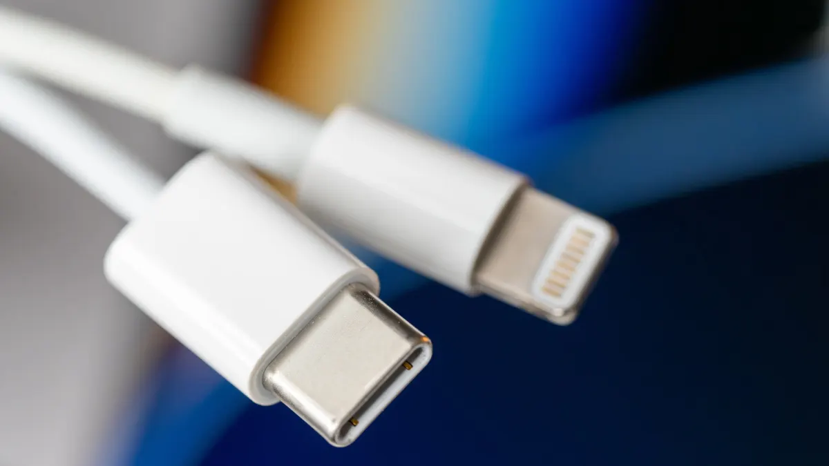 Ein weißes Ladekabel mit USB-C- und Lightning-Anschlüssen liegt auf blauem Grund.