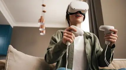 Eine Person mit einem weißen VR-Headset und Controllern in einem Wohnzimmer.