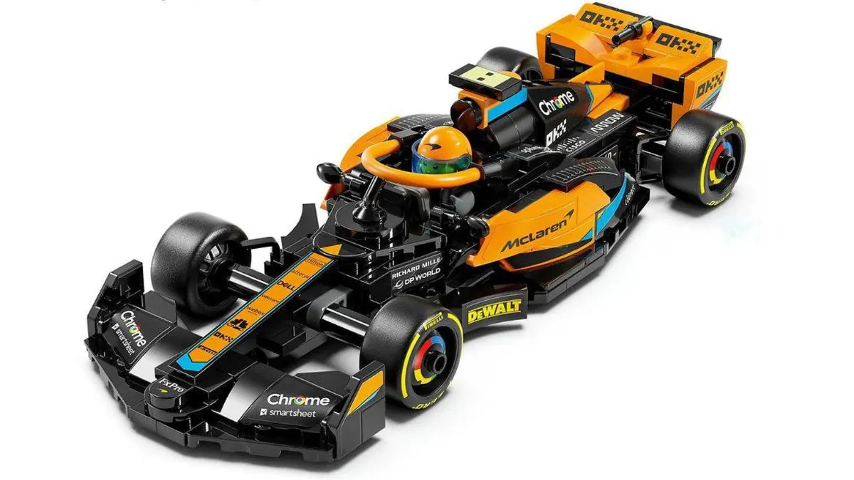 Ein schwarzes und orangefarbenes Spielzeug-Formel-1-Auto mit Logos und einem Fahrer mit gelbem Helm ist zu sehen.