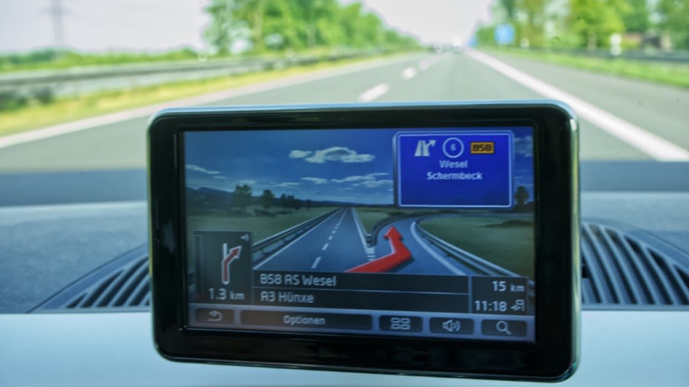 Ein Navigationsgerät hängt an der Scheibe im Auto und navigiert.