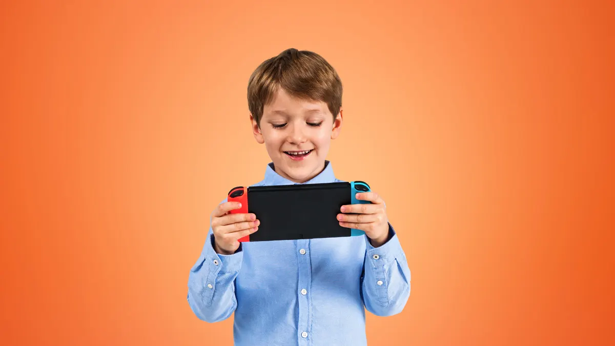 Ein lächelnder Junge hält ein Handheld in der Hand, dass an den Seiten rot und blau ist. Der Hintergrund des Bildes ist orange.