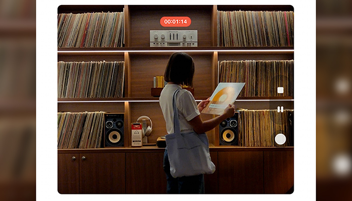 Person betrachtet ein Vinyl-Album vor einem Regal voller Schallplatten. 