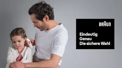 Ein Mann misst mit einem weißen Ohrthermometer bei einem kleinen Mädchen Fieber, Daneben weiß auf schwarzer Box das Braun-Logo und der Text: Eindeutig, Genau, die Sichere Wahl.