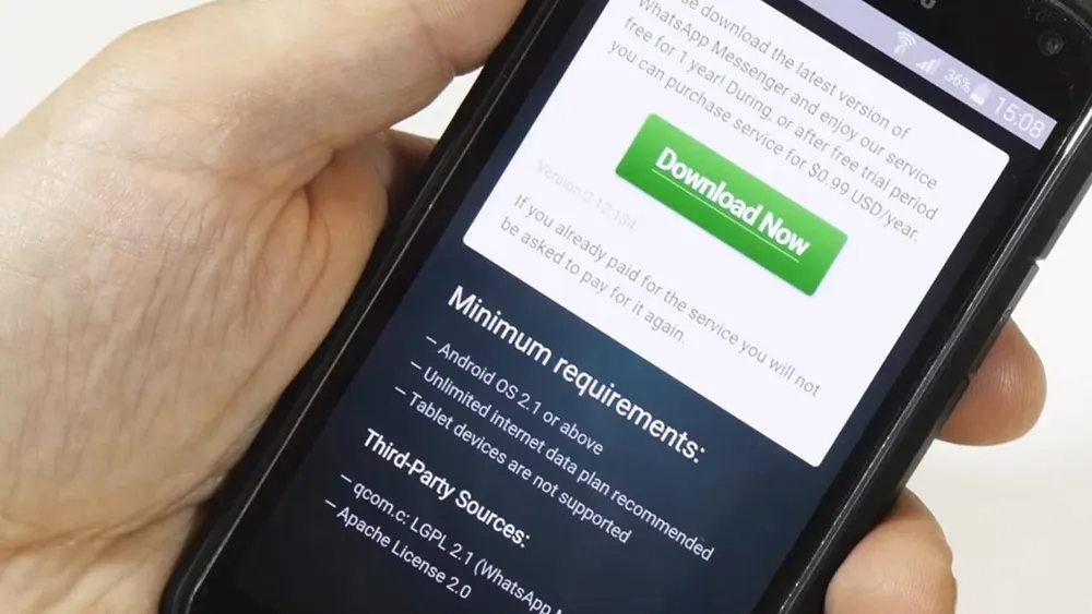 Eine Hand hält ein schwarzes Smartphone, auf dessen Bildschirm ein Download-Fenster mit grünem "Download Now"-Button angezeigt wird.