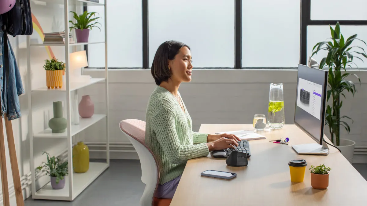 Eine Frau sitzt an einem Schreibtisch und tippt auf der Logitech-Tastatur Wave Keys.