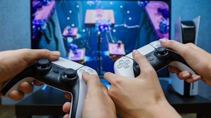 Zwei Gaming Controller werden vor einen Fernseher gehalten