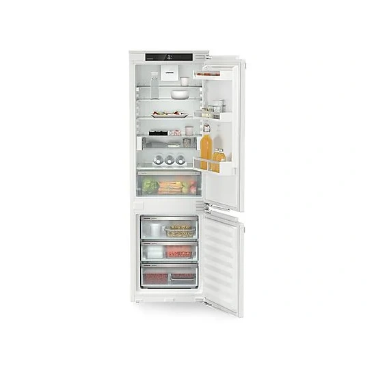 Ein geöffneter, weißer Kühlschrank mit Lebensmitteln auf Regalen und in Schubladen vor einem weißen Hintergrund.