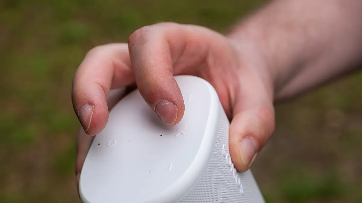 Finger liegen auf der Touchoberfläche des Sonos Play auf, während eine Hand den Lautsprecher hält.